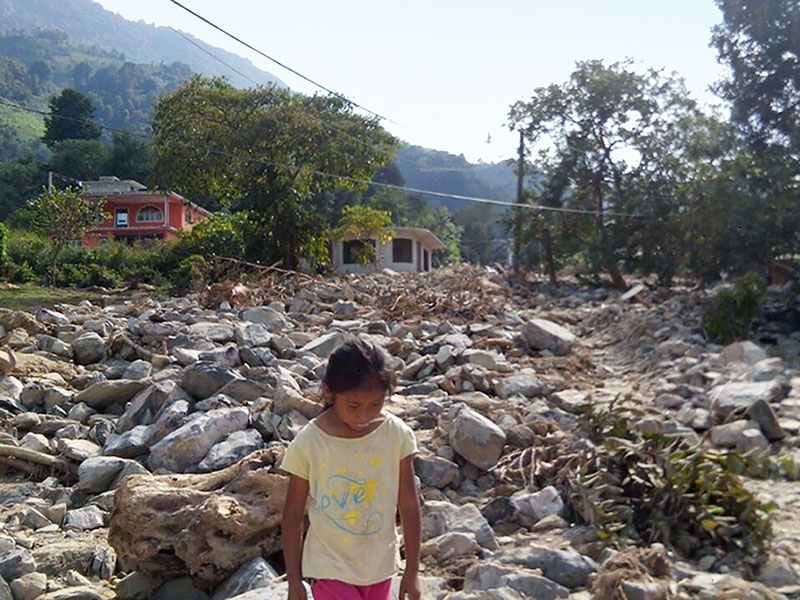 Girl walking through landslide remains from Tropical Storm Earl